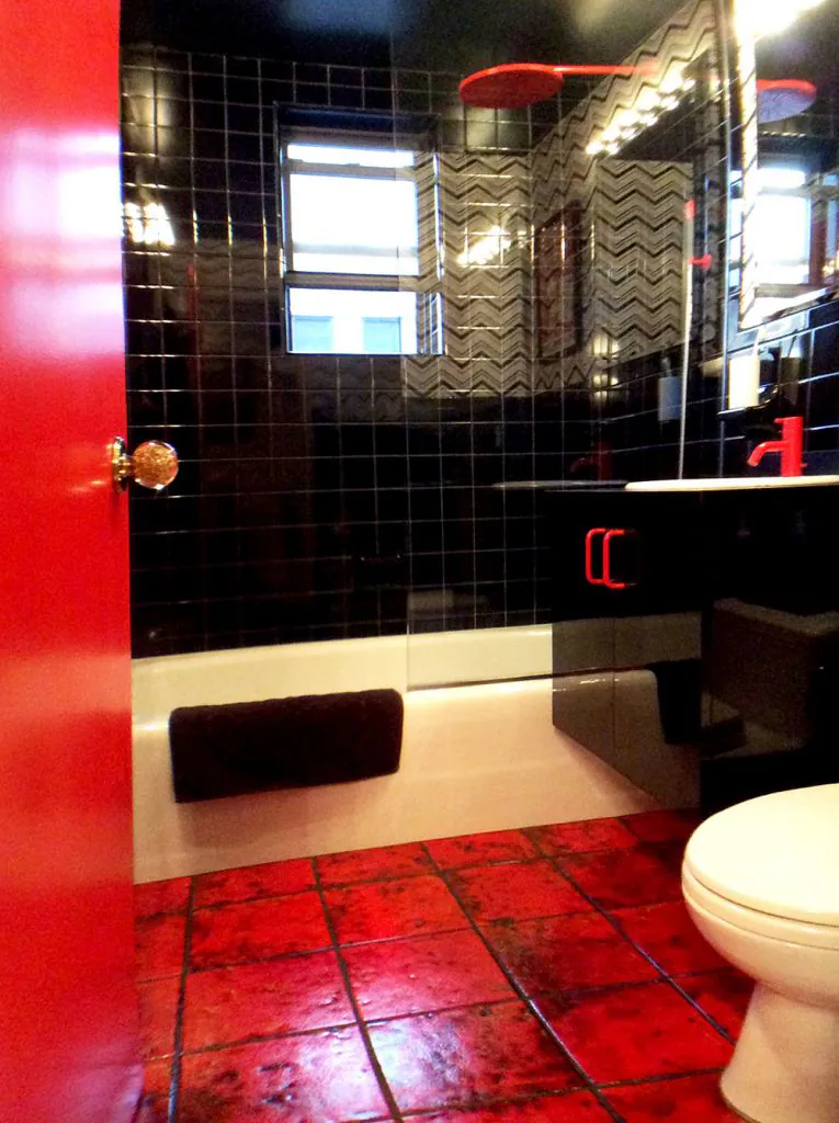 bathroom with black tile and red vola faucet