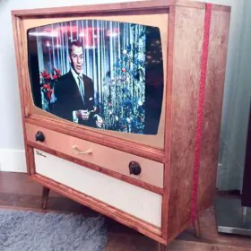 mid century tv box that holds a modern flatscreen tv