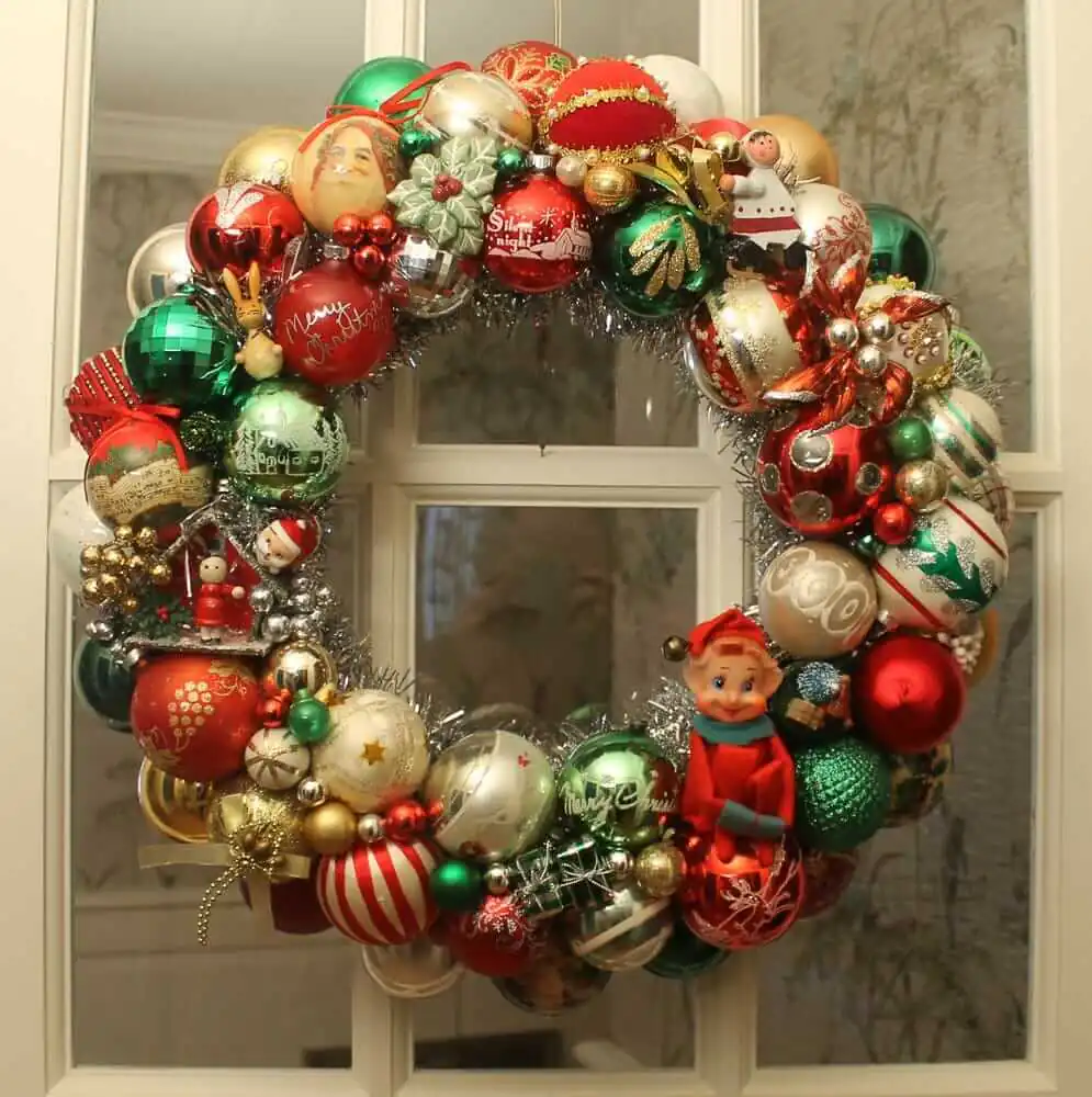 DIY Christmas ornament wreath made with red green and white ornaments and red knee hugger elf